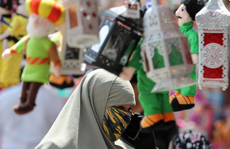 سيدة ترتدي كمامة وتقوم بشراء فانوس شهر رمضان الكريم 2020 من أحد الأسواق وقت تفشي فيروس كورونا امرأة ترتدي كمامة في سوق لفوانيس رمضان بمصر