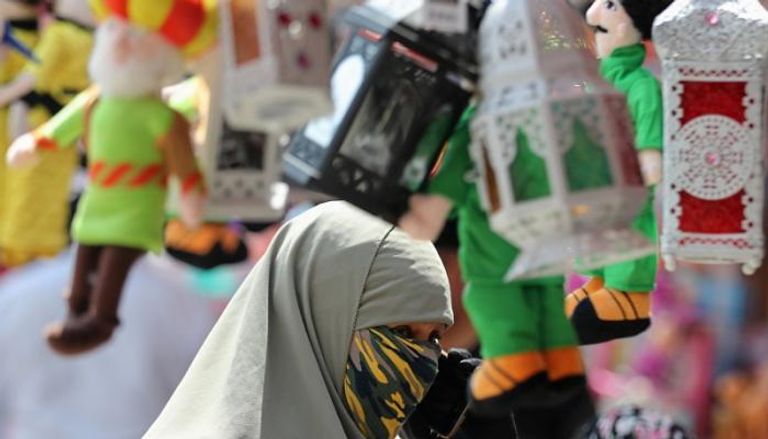 مصرية ترتدي الكمامة في أحد شوارع القاهرة وتستعد لشراء فانوس رمضان