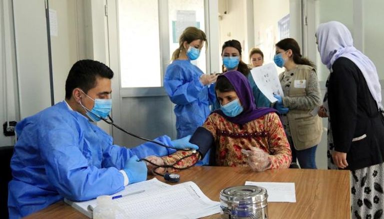 طبيب يفحص ضغط الدم لامرأة في العراق