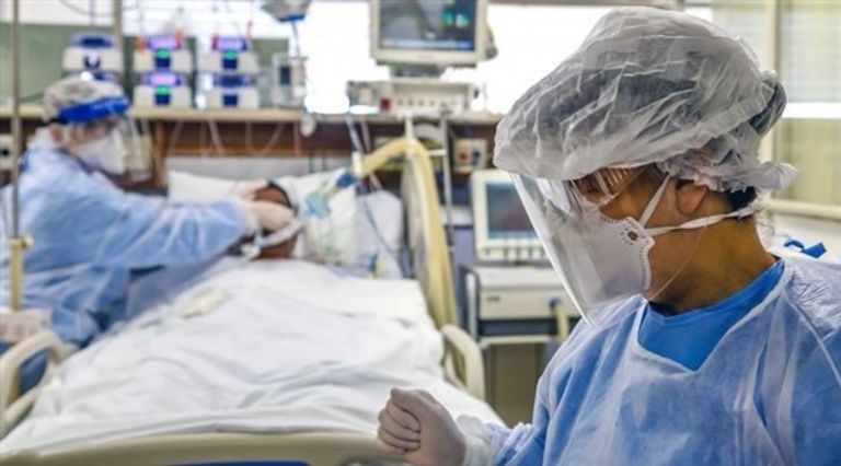 إحدى ضحايا فيروس كورونا ينقلها ممرضان إلى مقبرة في ماناوس