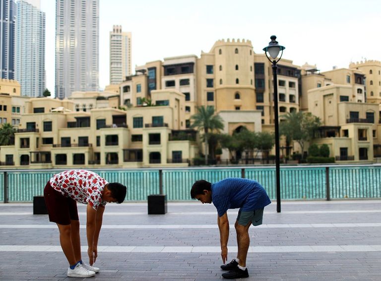 نساء يرتدين الكمامات ينتظرن دورهن أمام ماكينة صرف في دبي