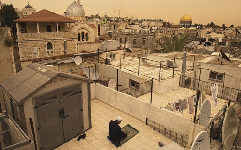 رجل يؤدي صلاة الظهر فوق سطح منزله في مدينة القدس