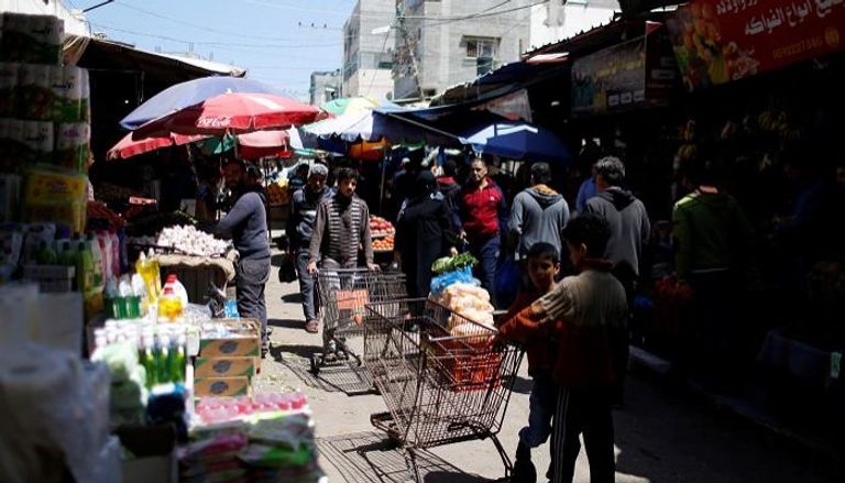 فلسطينيون يتسوقون في سوق بمخيم الشاطئ بغزة - رويترز