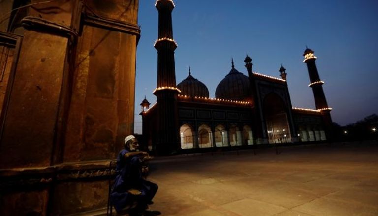 مسلم يتناول طعام فطوره بجوار مسجد مع حلول أذان المغرب