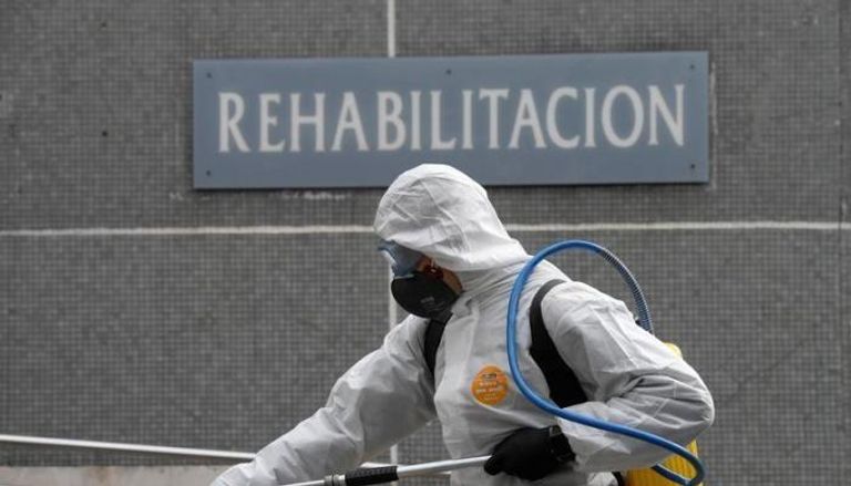 عمليات تعقيم للشوارع في إسبانيا عامل إغاثة إسباني يتحدث إلى مسنة قبل اختبار كورونا