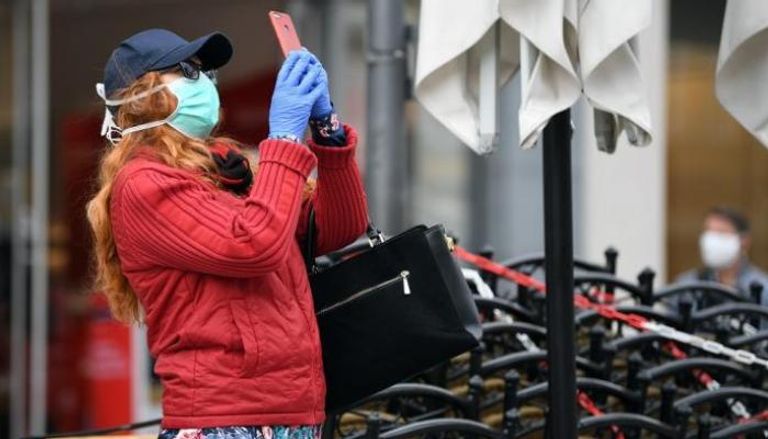 امرأة ترتدي كمامة وقفازات للوقاية من فيروس كورونا في ألمانيا