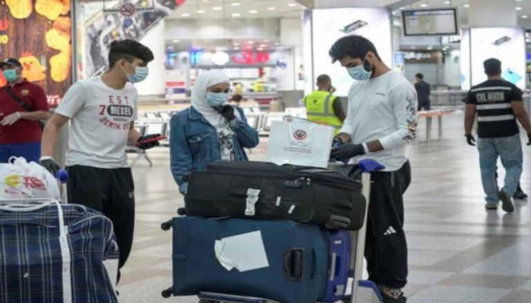 أشخاص يرتدون كمامات في مطار الكويت الدولي