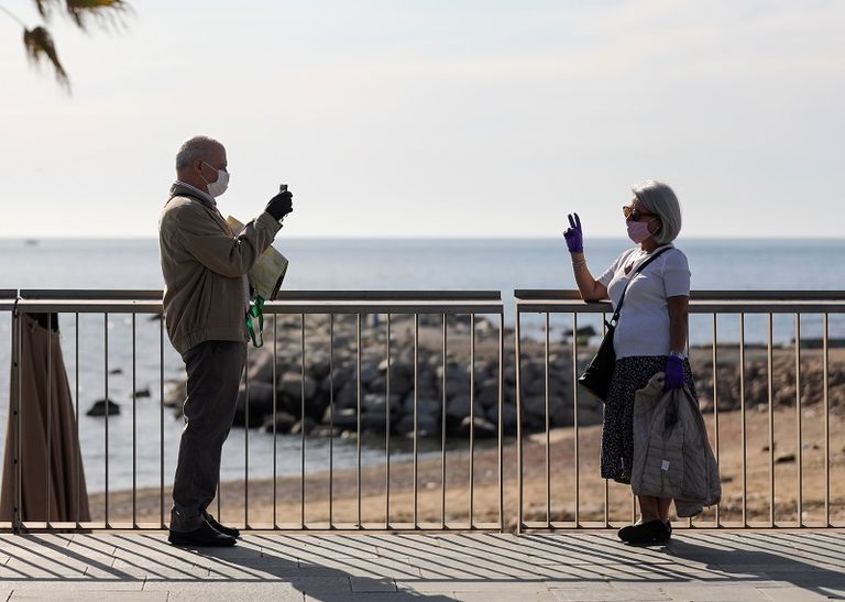 زوجان يرتديان أقنعة واقية يلتقطان صورة على شاطئ برشلونيتا خلال الساعات التي يُسمح فيها لكبار السن بالمشي في الهواء الطلق السماح للإسبان بالتريض لأول مرة منذ 7 أسابيع مع تخفيف إجراءات العزل