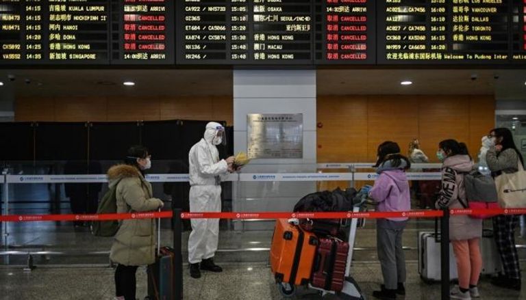 أحد موظفي الأمن الصينيين يرافق الركاب إلى حافلة ستنقلهم إلى شنغهاي