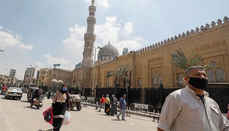 مصريون يرتدون الكمامات يمشون بجوار أحد مساجد القاهرة -رويترز