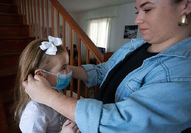 سيدة تساعد ابنتها في ارتداء القمامة أحد الأطفال يخضع لفحص الأجسام المضادة - ديلي ميل