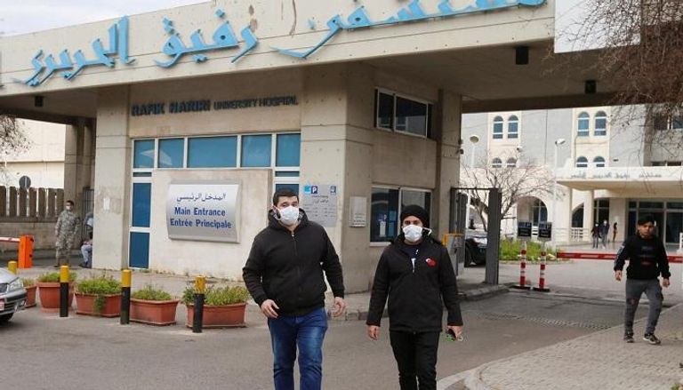 شخصان يرتديان الكمامات أمام مستشفى رفيق الحريري في بيروت