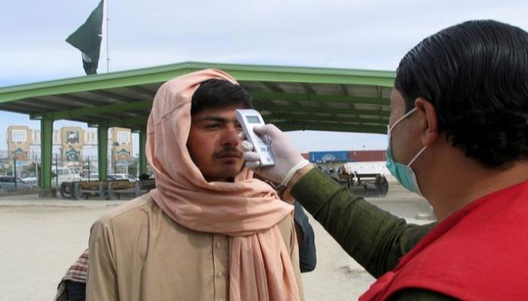 عامل صحي باكستاني يقيس درجة حرارة رجل عائد من أفغانستان 