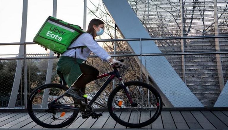 إحدى العاملات في أوبر إيتس تقود دراجة لتوصيل الطعام
