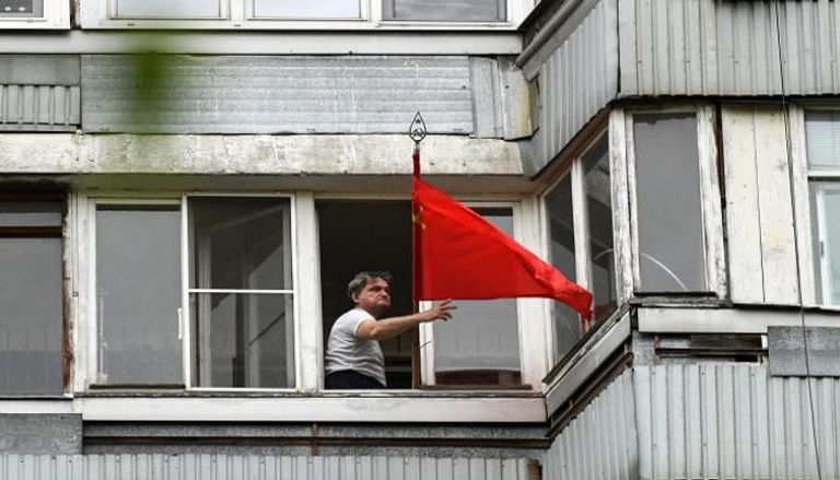 رجل روسي يلوح بعلم بلاده احتفالا بذكرى النصر 
