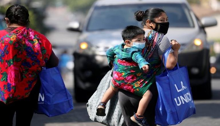 أم وطفلها يرتديان كمامة بأحد شوارع أمريكا