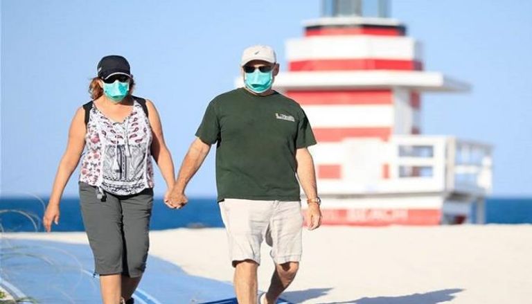 شخصان يرتديان كمامات على أحد الشواطئ الأمريكية