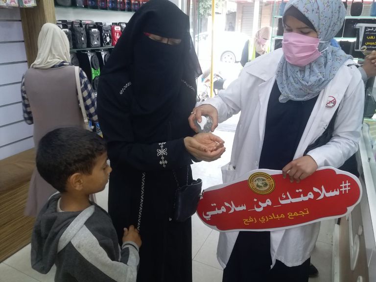 متطوعة تُلبِس صبية كمامة طبية