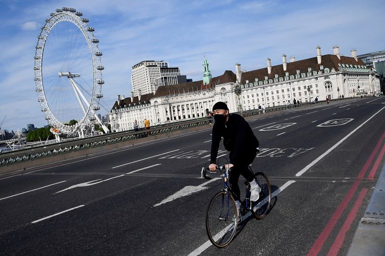 فتاة تقود دراجة بينما ترتدي كمامة في لندن