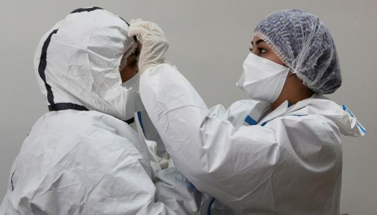 ممرضة تساعد زميلتها في تعديل معداتها الوقائية بأحد مستشفيات المغرب