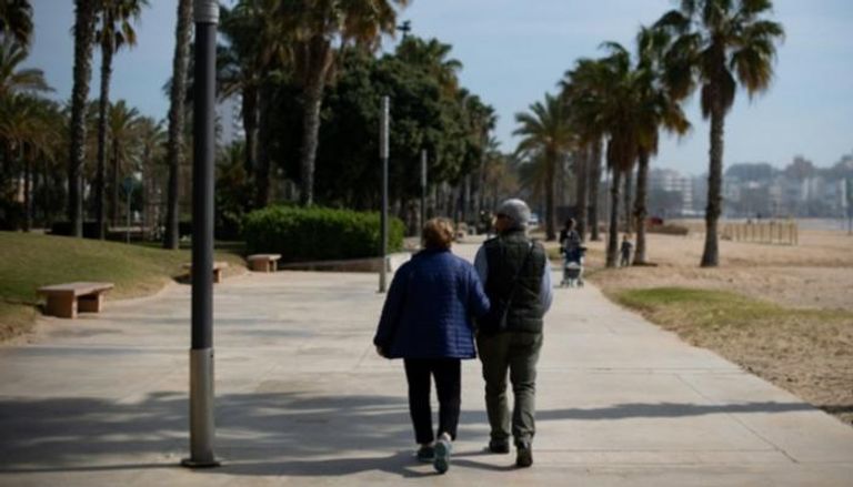 زوجان متقاعدان يتنزهان على شاطئ البحر في مدينة سالو
