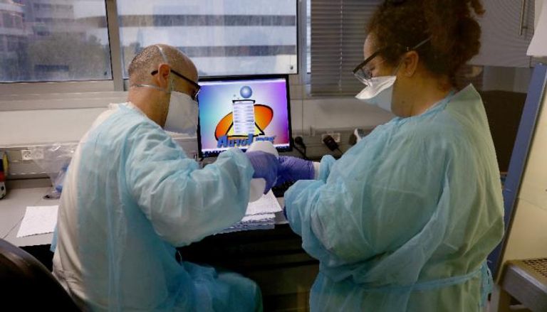 طبيبان إسرائيليان يجريان فحوصا على عينات من مرضى كورونا