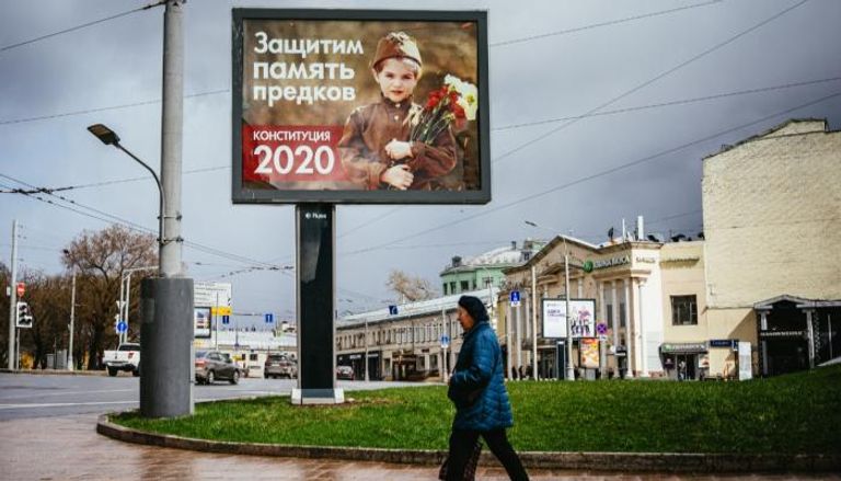 امرأة تمر من أمام لوحة إعلان استفتاء دستوري في موسكو
