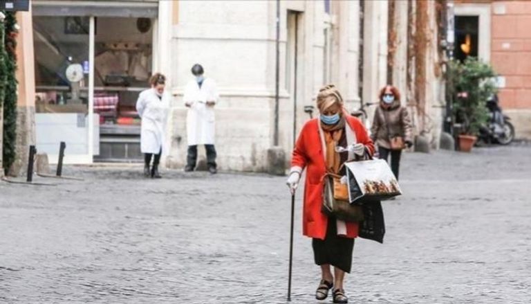 سيدة إيطالية ترتدي الكمامة أثناء سيرها في أحد شوارع إيطاليا