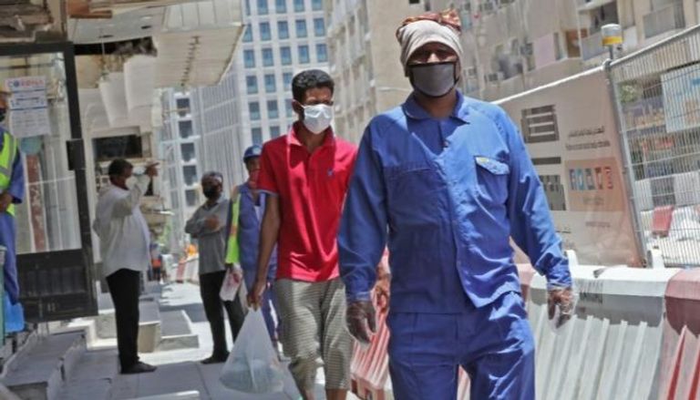 عمال يرتدون أقعنة وجه للوقاية من فيروس كورونا