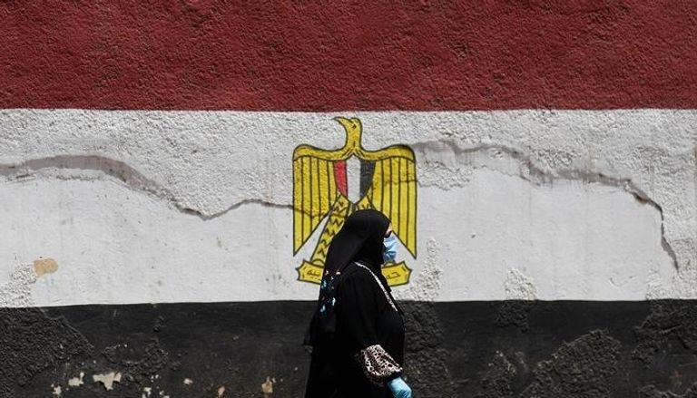 مصرية ترتدي الكمامة والقفازات الطبية للوقاية من كورونا