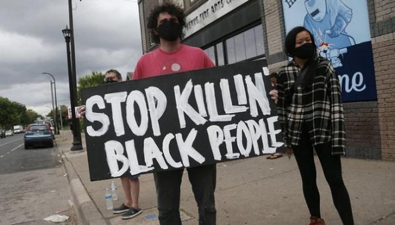 محتج يرفع لافتة بعد مقتل رجل من أصل أفريقي 