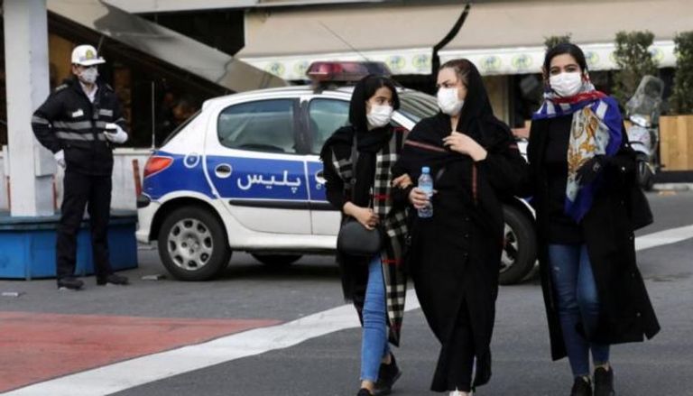 3 فتيات يرتدين الكمامات في أحد شوارع طهران