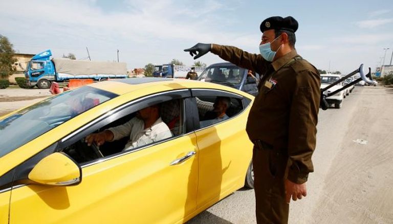 شرطي عراقي يرتدي الكمامة للوقاية من فيروس كورونا