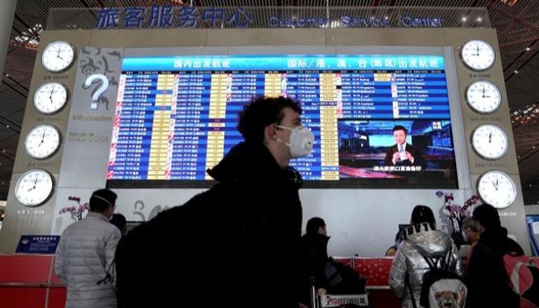 مسافر أجنبي يرتدي قناعا في مطار بكين الدولي - رويترز