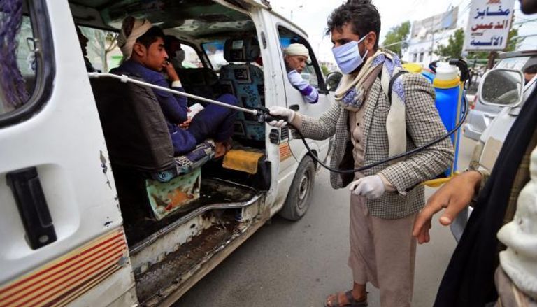 عامل يمني يتولى تعقيم سيارة ميكروباص في اليمن