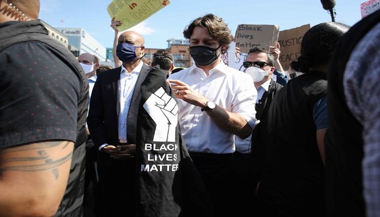 جاستن ترودو يحمل بين يديه قميصا أسود كتب عليه "بلاك لايفز ماتر" جاستن ترودو جثا مرات عدة امتدت آخرها لثماني دقائق و46 ثانية