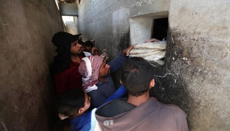 سوريون يشترون الخبز في بلدة بنش بمحافظة إدلب - أ ف ب