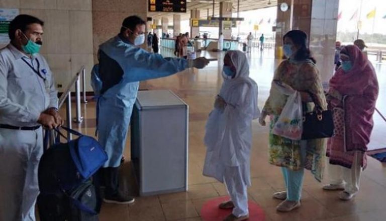 عامل في مطار كراتشي يتأكد من حرارة المسافرين- أرشيفية 