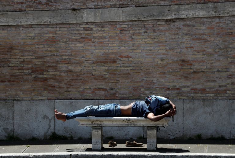 برازيلي يرتدي الكمامة ويسير بجوار حائط عليه جرافيتي عن مكافحة الفيروس