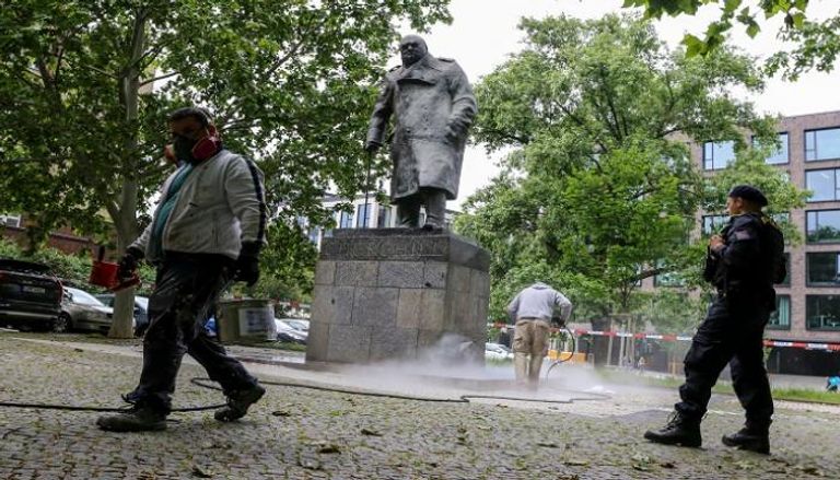 عمال ينظفون تمثال ونستون تشرشل في وسط لندن بعدما تعرض لعملية تخريب