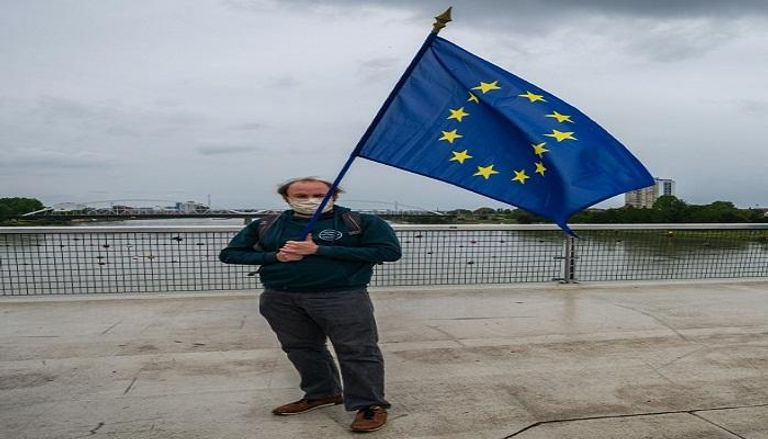 رجل يرفع العلم الأوروبي على جسر يربط بين فرنسا وألمانيا