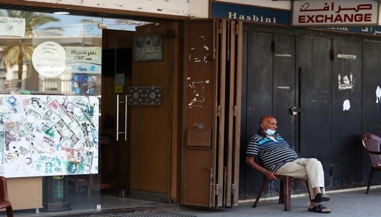 رجل يجلس خارج متجر للصرافة في بيروت - رويترز