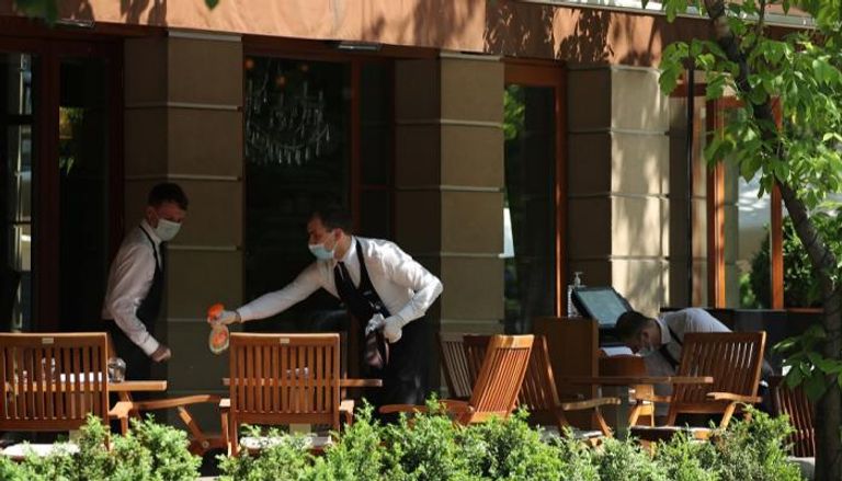 عامل يرش المطهرات على طاولات أحد المطاعم في موسكو