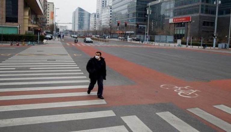 رجل يرتدي قناعا أثناء سيره في حي الأعمال ببكين - رويترز