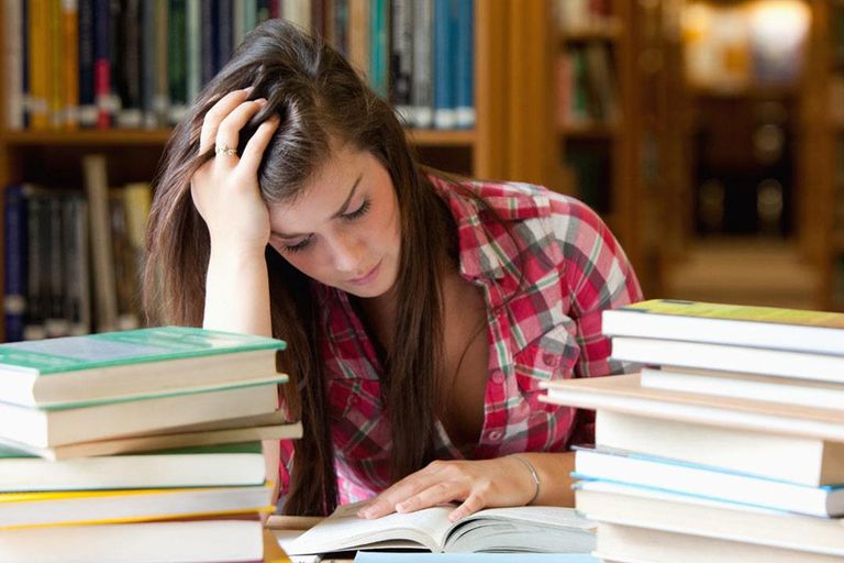 فتاة تتصفح كتاب يجب تخفيف الضغط النفسي على الطلاب خلال فترة الامتحانات