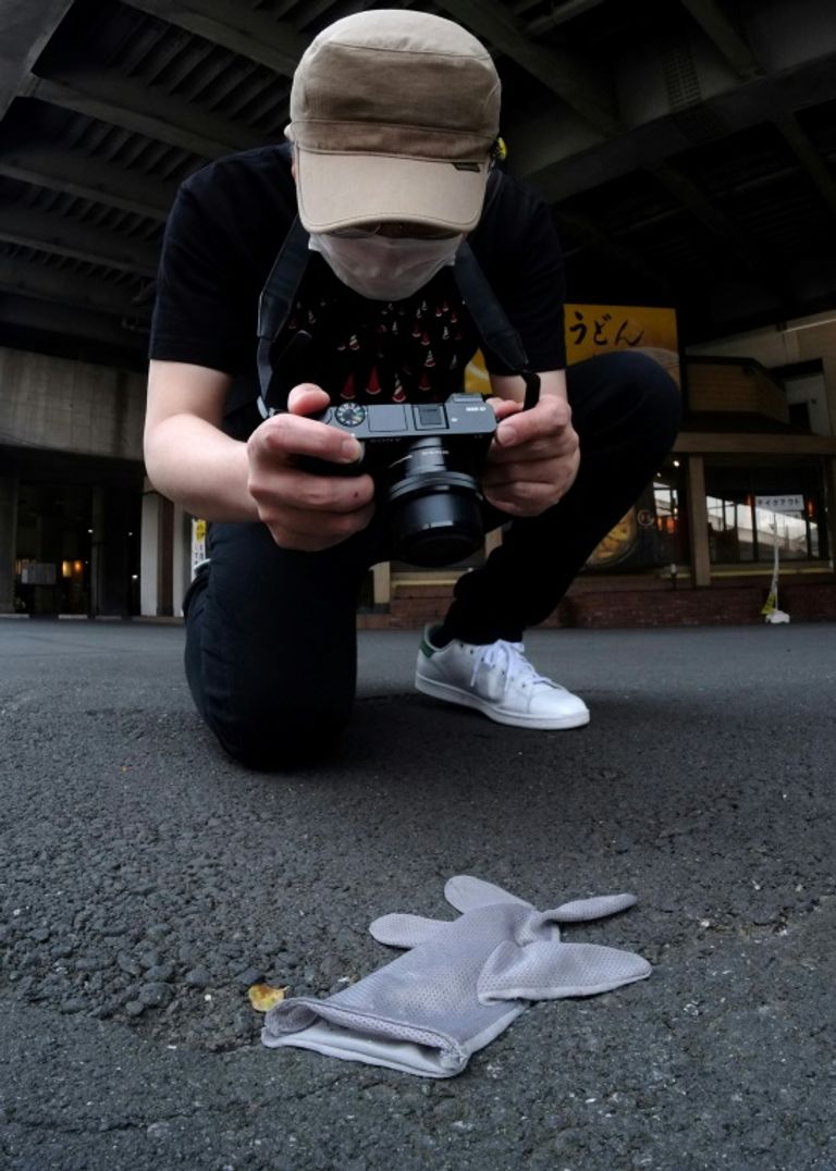 كوجي إيشي يقوم بتصوير قفاز ملقى في أحد شوارع اليابان