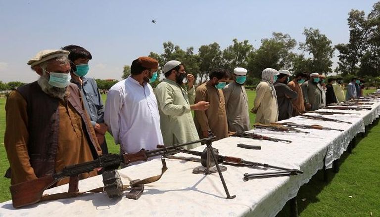 عناصر حركة طالبان وأمامهم أسلحة وذخيرة