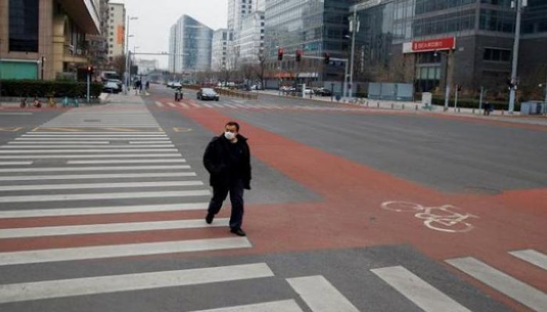 رجل يرتدي قناعا أثناء سيره في حي الأعمال ببكين - رويترز