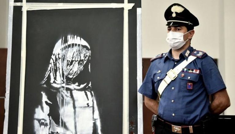 شرطي إيطالي بجانب جدارية بانكسي