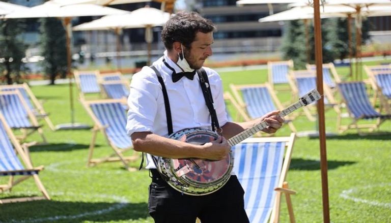 شخص يعزف الألحان على الشاطئ ميلانو تبتكر شاطئا خاصا بين ناطحات السحاب